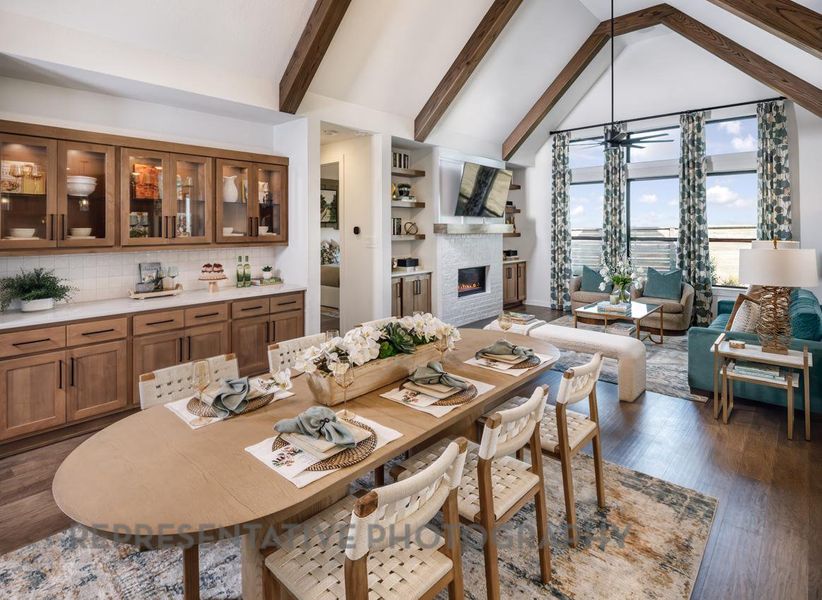 Dining space featuring a glass covered fireplace, dark wood-type flooring, beamed ceiling, and high vaulted ceiling