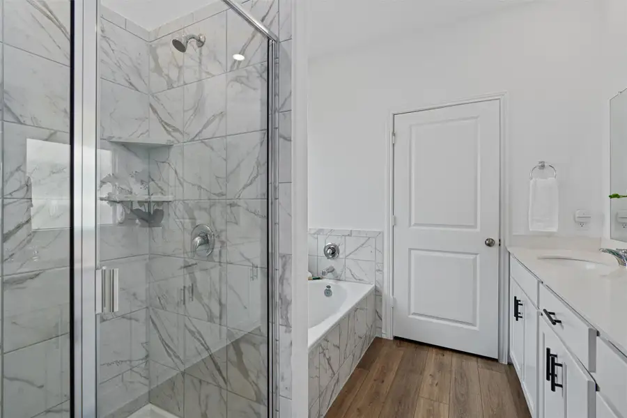 Bathroom with a garden tub, vanity, wood finished floors, and a marble finish shower