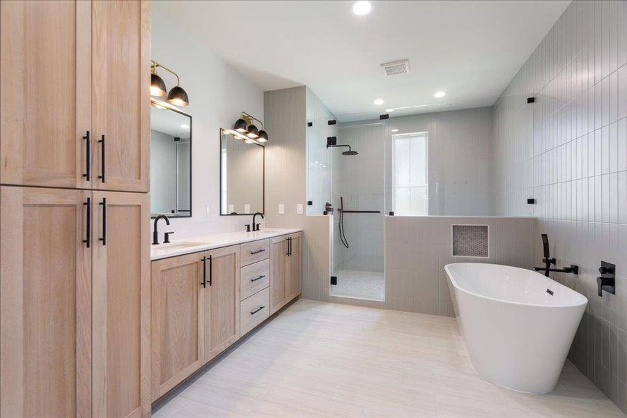 Full bath with tile walls, a shower stall, double vanity, a freestanding bath, and recessed lighting