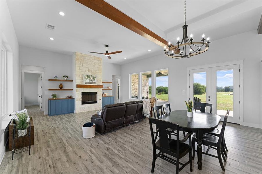 Spacious living area featuring wood-finish flooring, a stone fireplace with a wood mantle, and built-in shelving