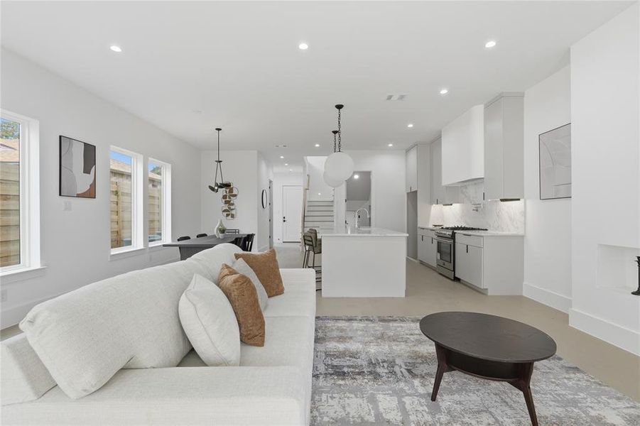 Open-concept living area featuring light wood-finish flooring, recessed lighting, and multiple windows