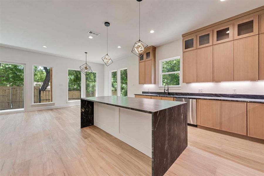 Kitchen featuring recessed lighting, dishwasher, light wood-type flooring, a kitchen island, and glass insert cabinets