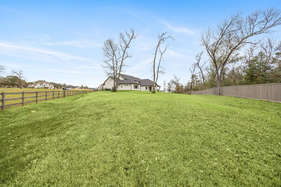 A spacious property with a large, lush green lawn. The setting is open and serene, offering privacy and plenty of outdoor space.