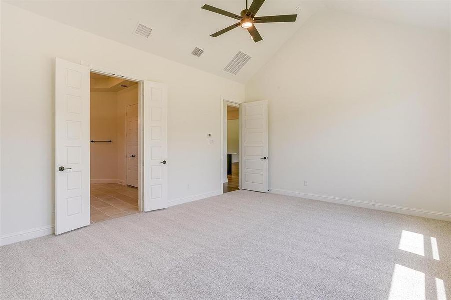 Unfurnished bedroom featuring light carpet, ceiling fan, and high vaulted ceiling