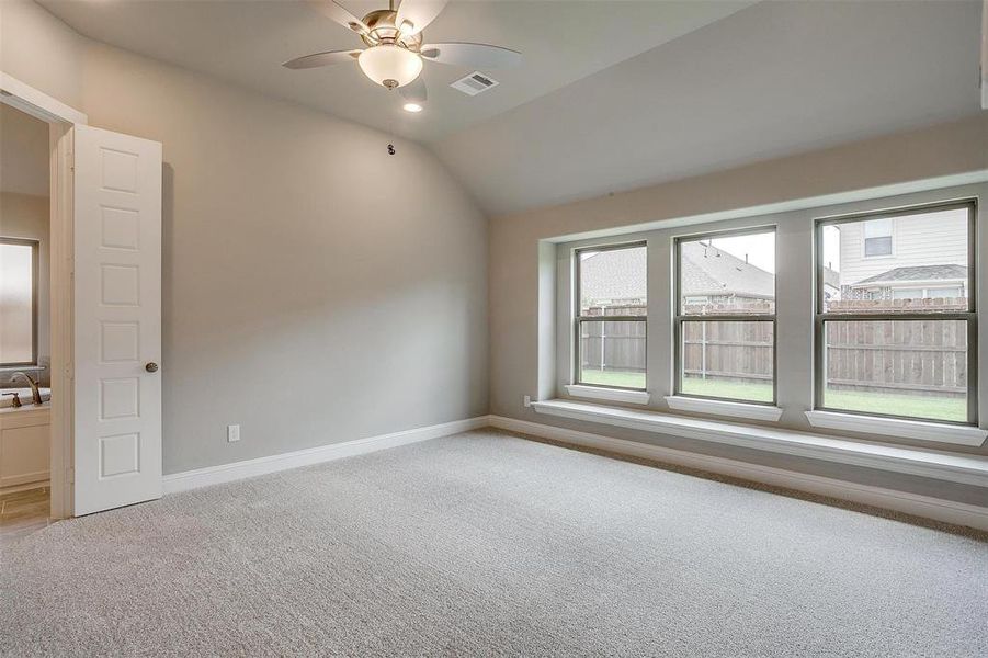 Empty room featuring ceiling fan, lofted ceiling, and light colored carpet