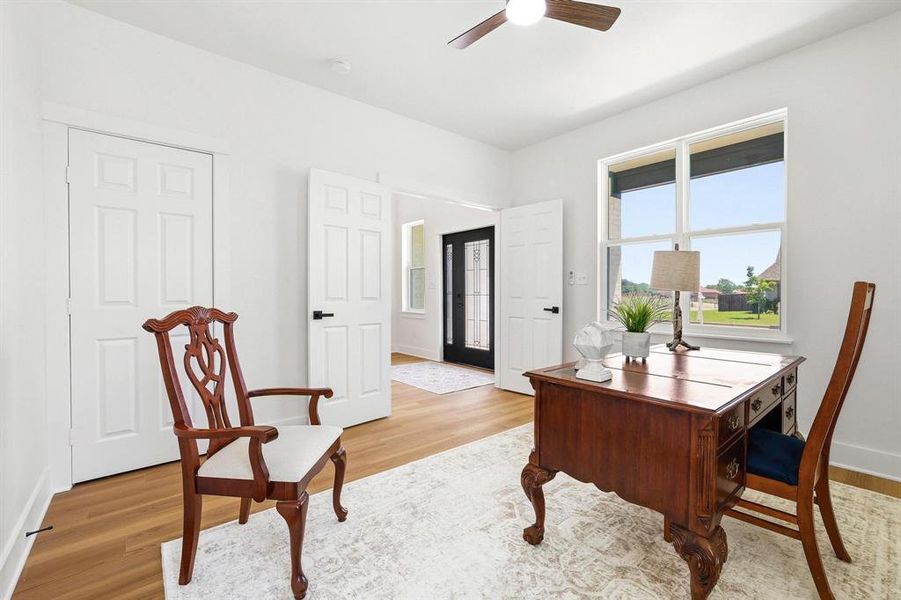 Versatile room featuring wood-finish flooring, a ceiling fan, and a large window Versatile room featuring wood-finish flooring, a ceiling fan, and a large window