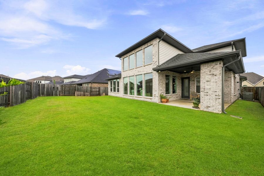 A view of the expansive backyard and covered patio highlights an inviting extension of the home, offering a comfortable setting for outdoor dining, entertaining guests or simply enjoying the privacy and open surroundings.