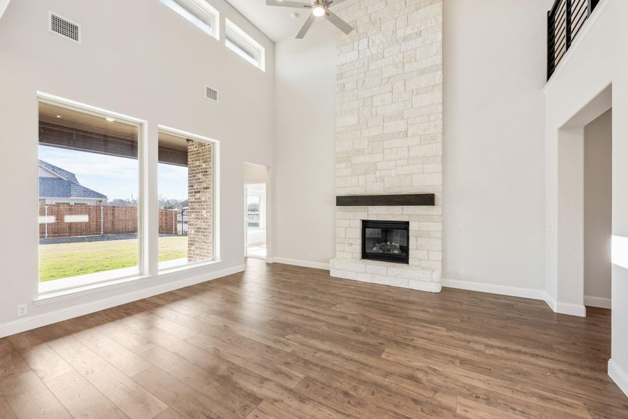 Open living room with vaulted ceiling, floor-to-ceiling stone fireplace, hardwood floors, and large windows Open living room with vaulted ceiling, floor-to-ceiling stone fireplace, hardwood floors, and large windows