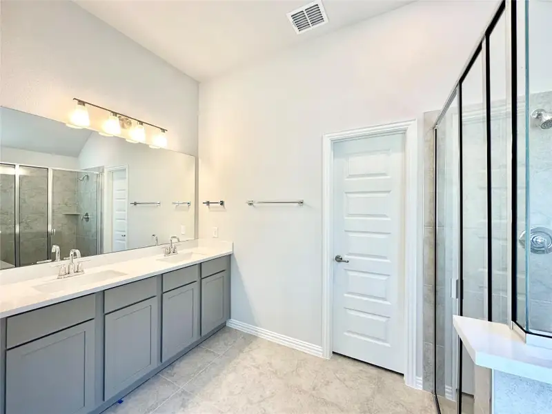 Full bathroom with a shower stall, double vanity, and light tile patterned flooring Full bathroom with a shower stall, double vanity, and light tile patterned flooring