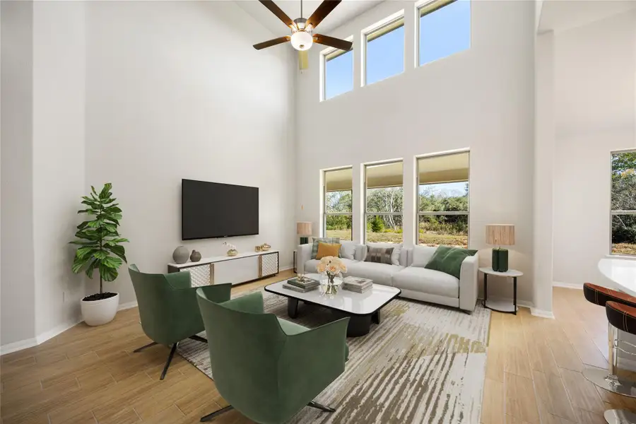 This impressive two-story family room is designed for modern living. It creates a grand sense of openness and drama with its soaring double-height ceiling and a stunning bank of large windows. The ceiling fan is centered high in the valted space, adding a focal point and aiding air circulation. *Virtually Staged This impressive two-story family room is designed for modern living. It creates a grand sense of openness and drama with its soaring double-height ceiling and a stunning bank of large windows. The ceiling fan is centered high in the valted space, adding a focal point and aiding air circulation. *Virtually Staged