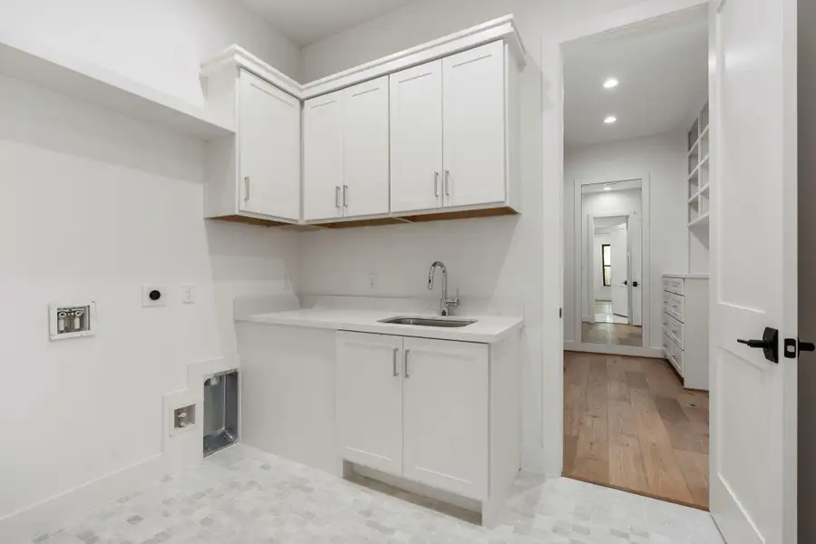 One of the primary closets leads into the utility room with sink One of the primary closets leads into the utility room with sink