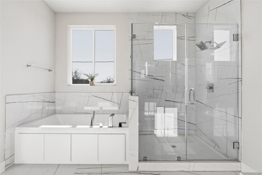 The primary bath is designed around proportion: an oversized soaking tub set beneath natural light, balanced by a frameless glass shower that allows the tilework and volume of the room to take center stage. Clean lines, minimal visual breaks, and a layout that feels calm rather than crowded.