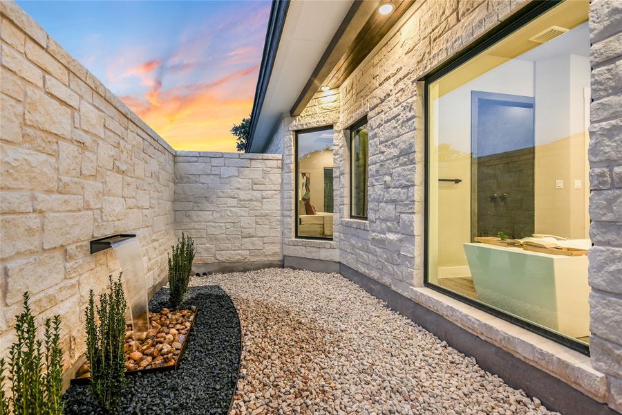 Property exterior at dusk featuring stone siding and a private courtyard with water feature Property exterior at dusk featuring stone siding and a private courtyard with water feature