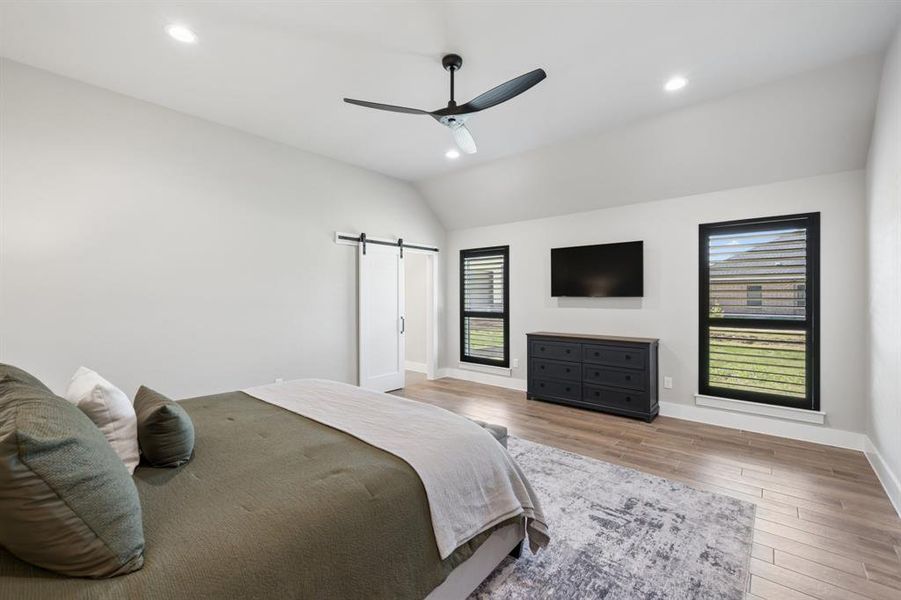 Bedroom featuring wood finished floors, recessed lighting, vaulted ceiling, a barn door, and a ceiling fan