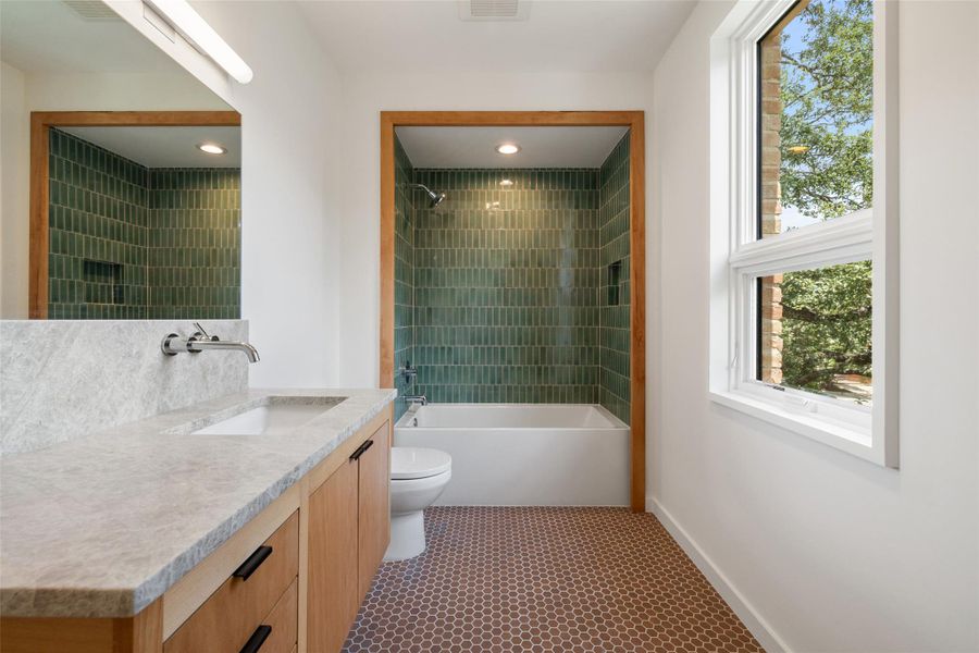Bathroom featuring washtub / shower combination, vanity, and dark tile patterned flooring