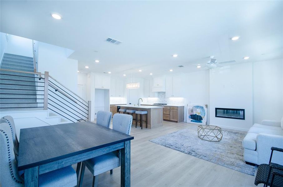 Dining space featuring light wood-style floors, a glass covered fireplace, ceiling fan, and recessed lighting