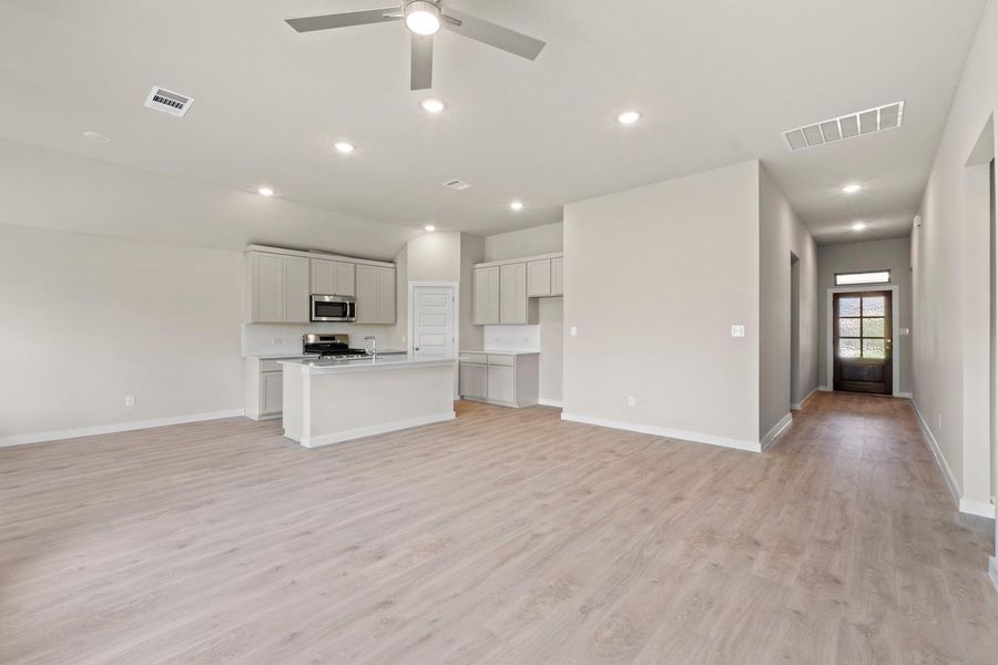 An open-concept living space integrates a functional kitchen with an inviting entryway, all under bright recessed lighting.