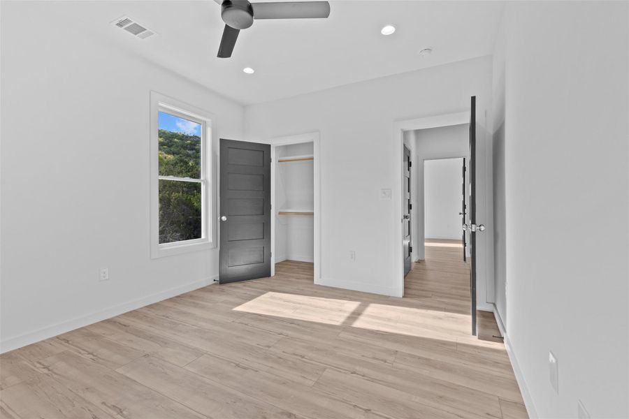 Unfurnished bedroom featuring a ceiling fan, a spacious closet, recessed lighting, and light wood-style flooring