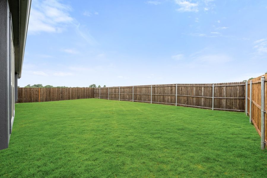 Spacious backyard with green grass lawn and full wood privacy fence enclosure