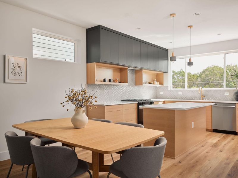 Kitchen with modern cabinets, light wood-style floors, pendant lighting, and backsplash