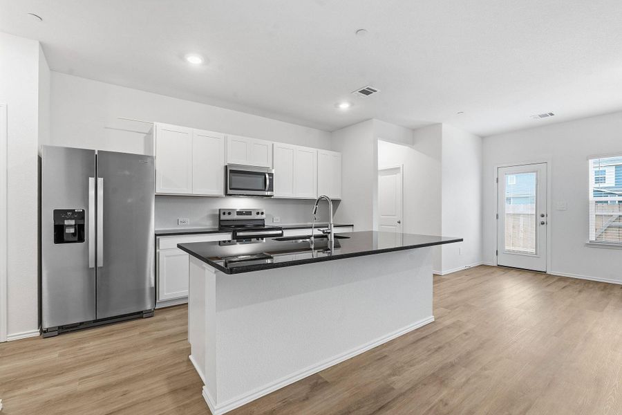 Kitchen featuring a central island with a dark countertop, white cabinetry, and stainless steel appliances