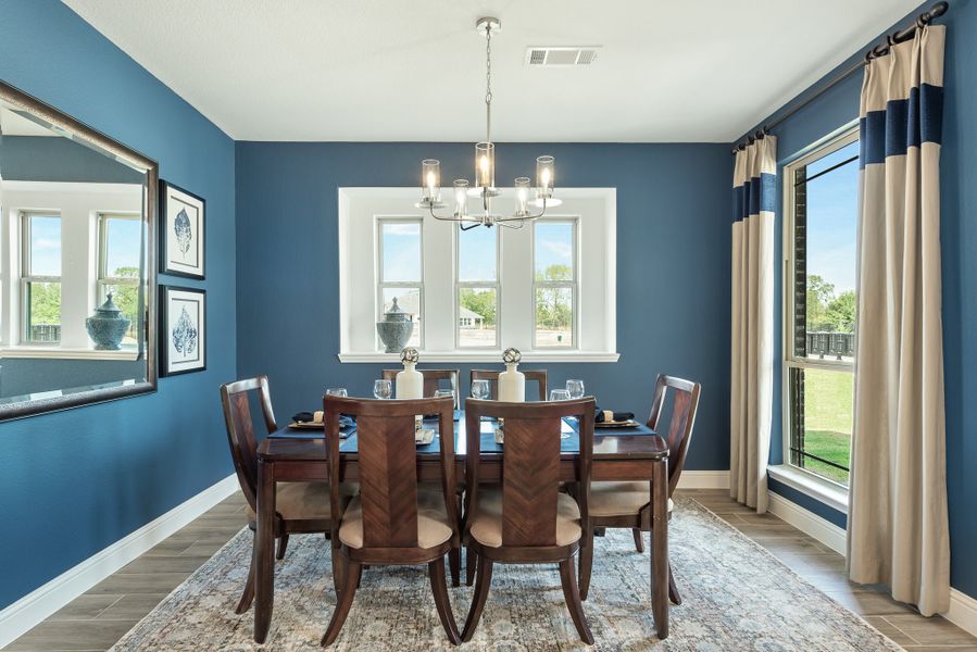 Dining room with dark wood table, six chairs, chandelier, and blue walls