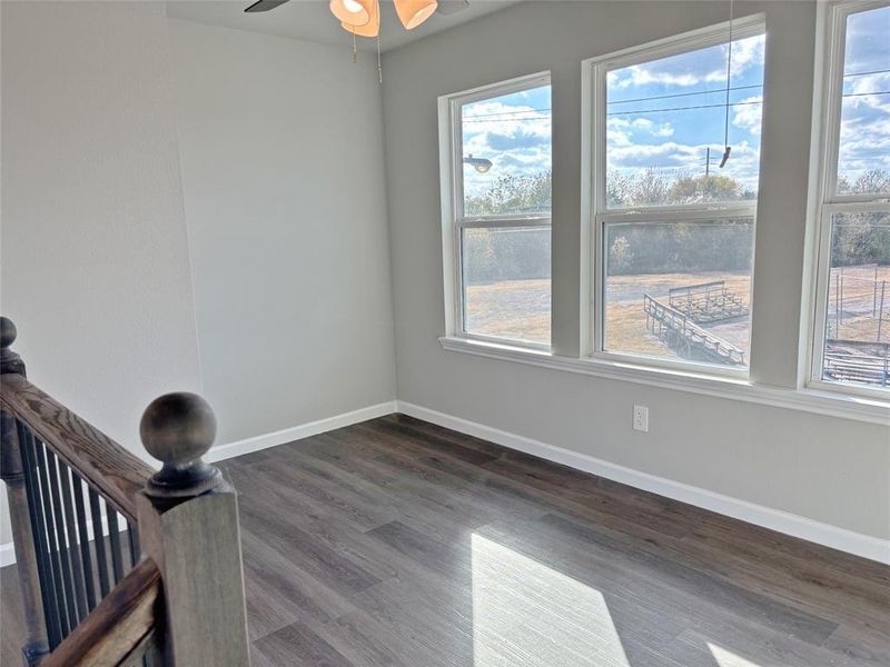 Empty room with dark wood-style flooring and a ceiling fan