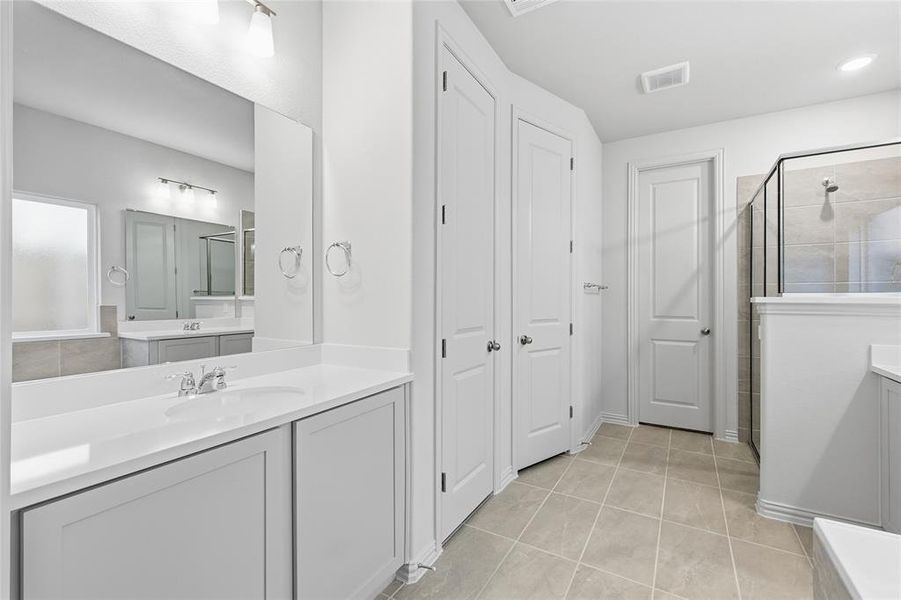 Bathroom with two vanities, a shower stall, light tile patterned floors, a tub, and a closet