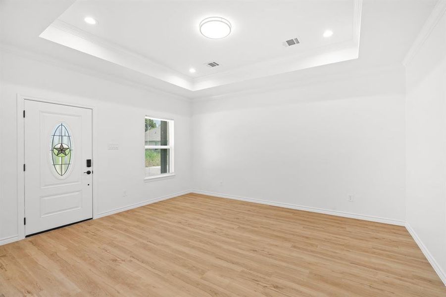 Entrance foyer with a raised ceiling, crown molding, light wood-style floors, and recessed lighting Entrance foyer with a raised ceiling, crown molding, light wood-style floors, and recessed lighting