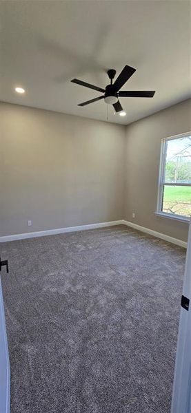 Bedroom featuring a ceiling fan and dark colored carpet Bedroom featuring a ceiling fan and dark colored carpet