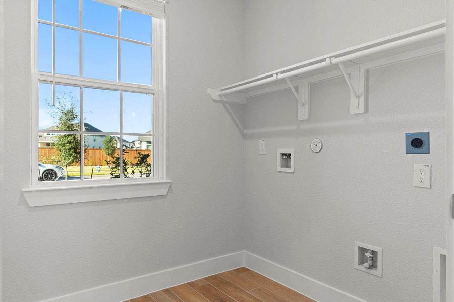 Downstairs a bright, organized utility room adds convenience to daily life, featuring built-in shelving, natural light, and washer/dryer connections. Function meets comfort in this well-designed space—another thoughtful CastleRock touch.