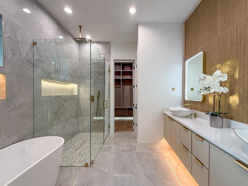 Full bathroom featuring a marble finish shower, a freestanding tub, double vanity, light marble finish floors, and a walk in closet