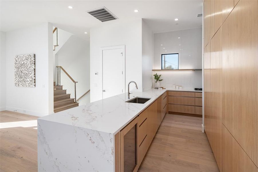 Kitchen featuring sink, light hardwood / wood-style flooring, light stone countertops, light brown cabinetry, and kitchen peninsula