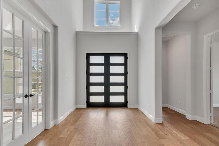 Foyer entrance with light wood-type flooring and french doors