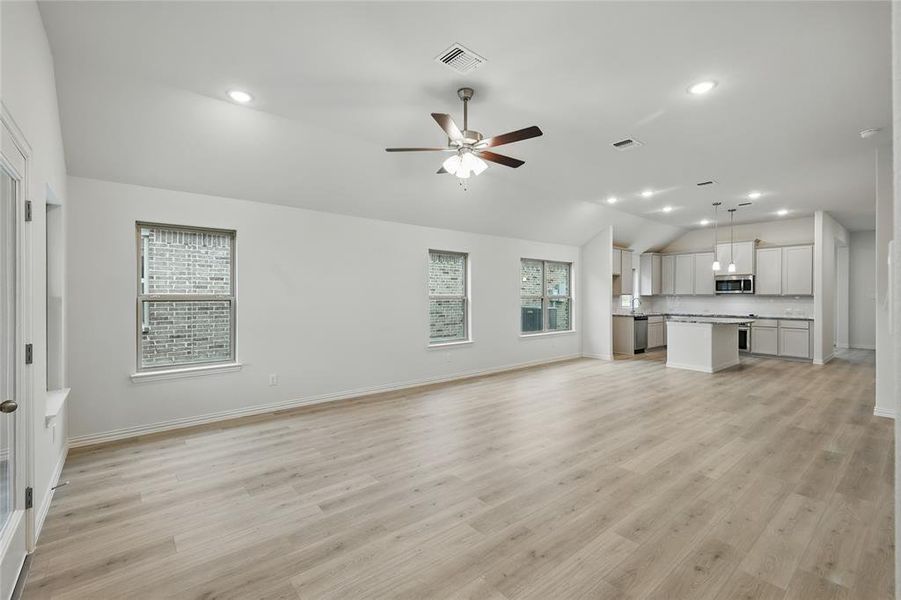 Unfurnished living room featuring recessed lighting, a ceiling fan, lofted ceiling, and light wood finished floors