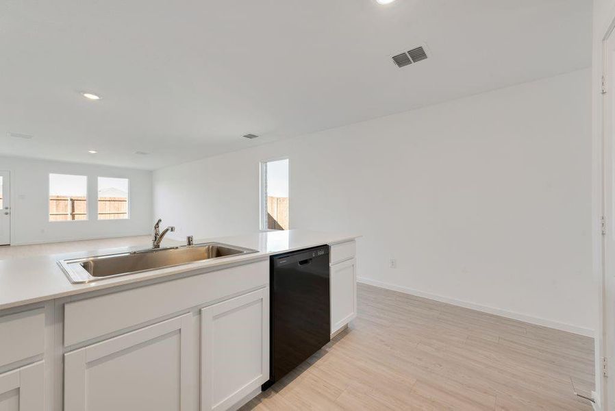 Kitchen with light wood-type flooring, black dishwasher, recessed lighting, white cabinets, and light countertops