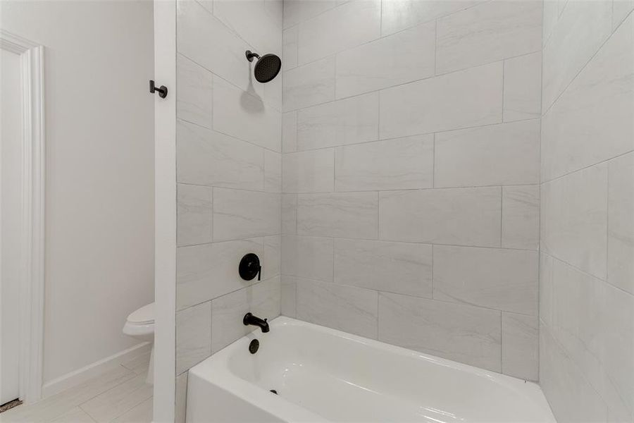 Bathroom with toilet and tiled shower / bath combo