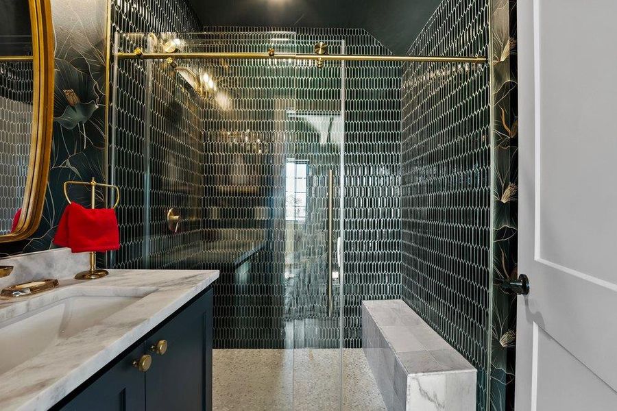 Bathroom with vanity, a stall shower, and tile walls