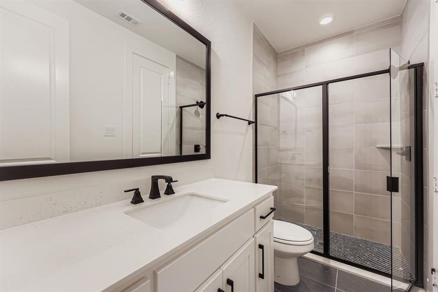 Bathroom with a shower stall, vanity, dark tile patterned flooring, and recessed lighting