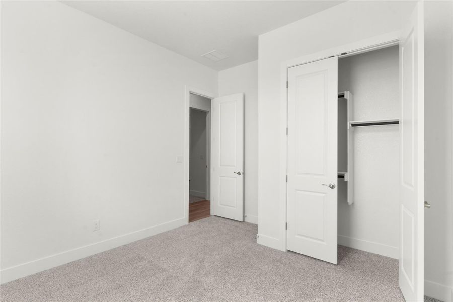 Unfurnished bedroom featuring light carpet and a closet