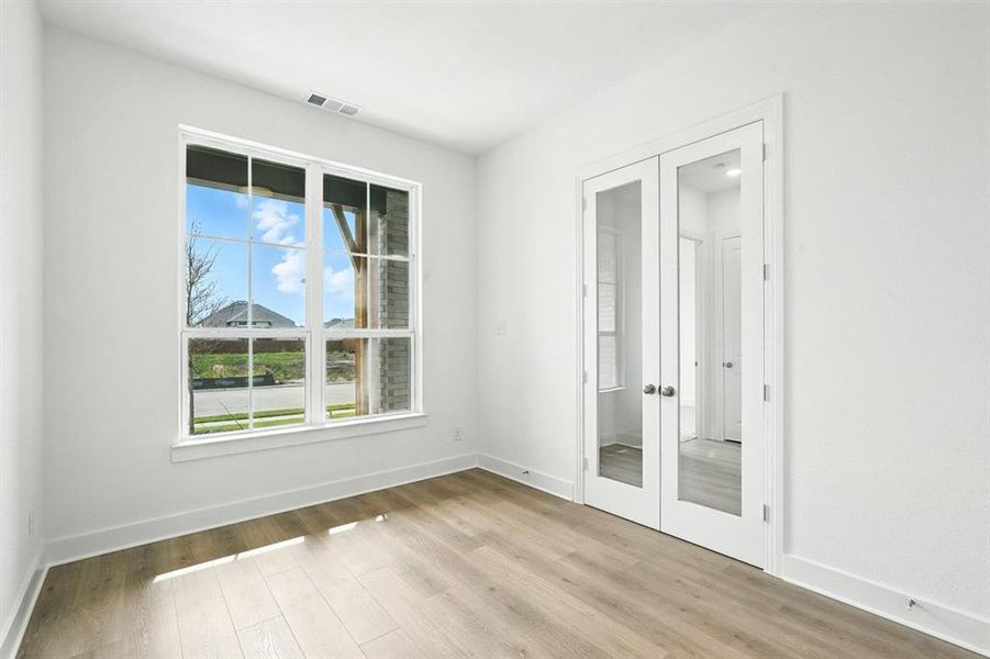 Unfurnished room with french doors and light wood-style flooring Unfurnished room with french doors and light wood-style flooring