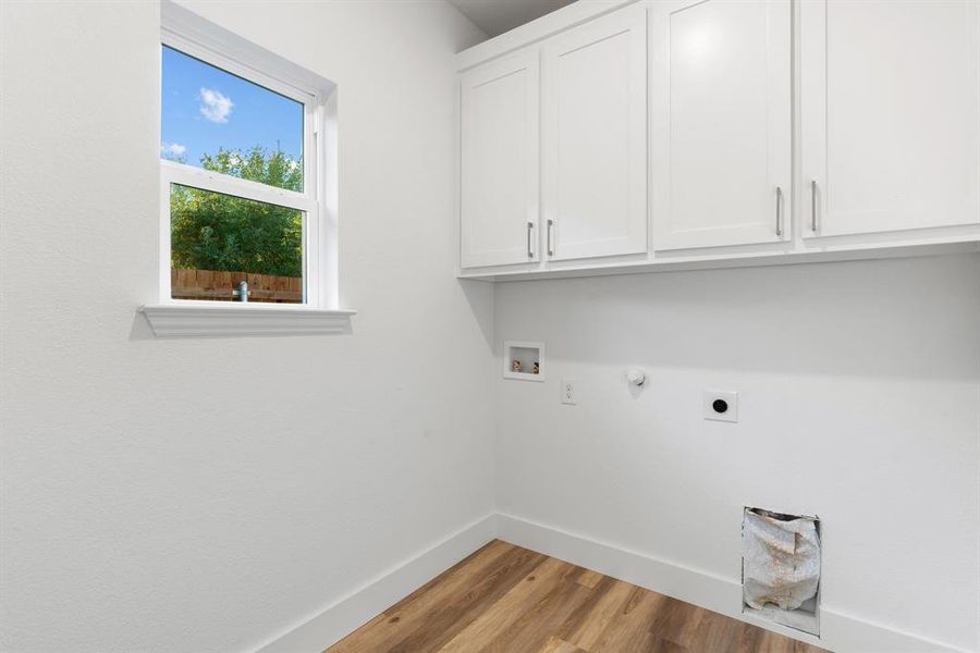 Clothes washing area featuring hookup for an electric dryer, gas dryer hookup, cabinets, hookup for a washing machine, and light wood-type flooring