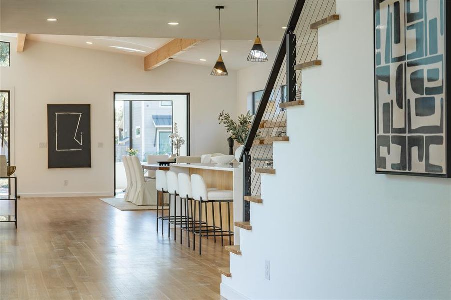 Dining space featuring vaulted ceiling with beams and light hardwood / wood-style flooring