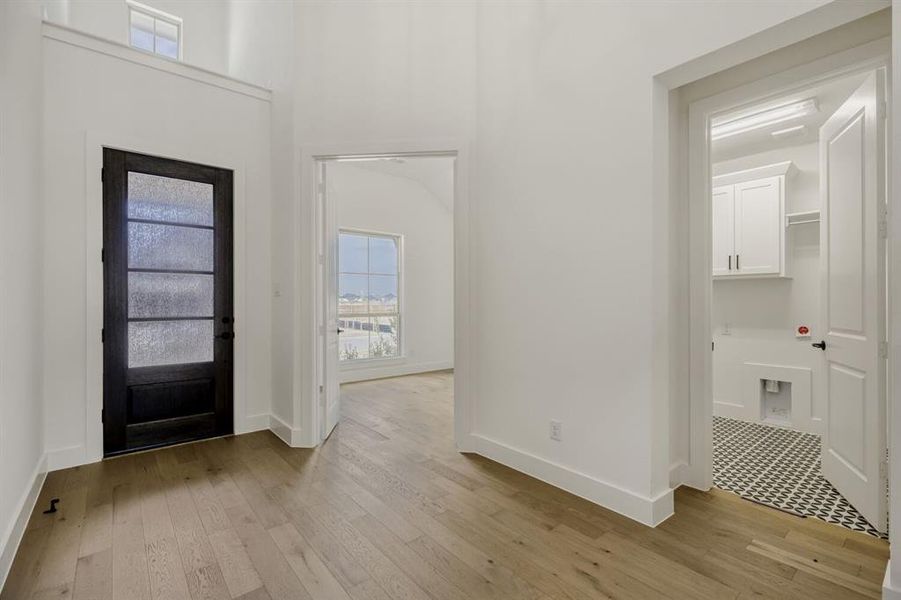 Entrance foyer with light wood-type flooring and a high ceiling