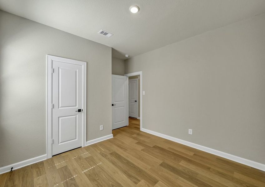 Secondary bedroom featuring a closet, a doorway to the hall, and wood-look flooring.