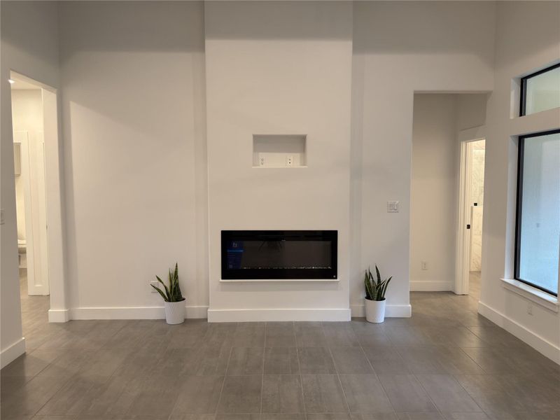 Unfurnished living room featuring a glass covered fireplace and baseboards Unfurnished living room featuring a glass covered fireplace and baseboards