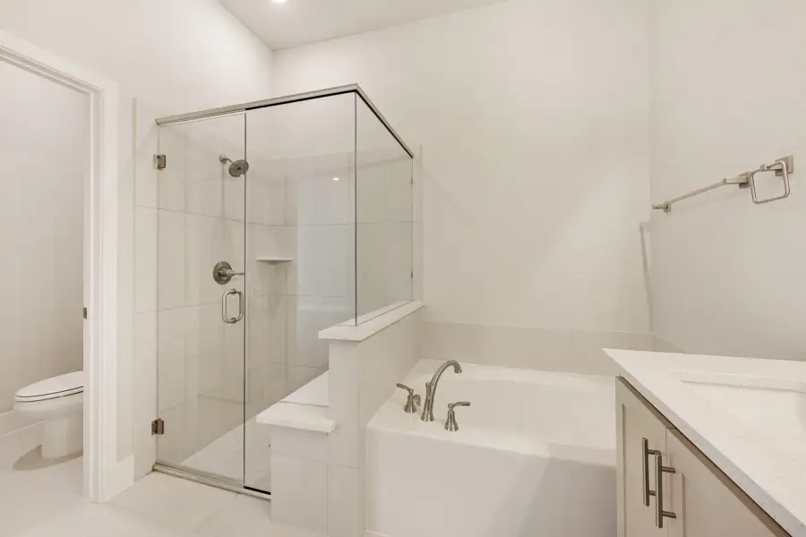 Bathroom with glass walk-in shower, soaking tub, white tile, and vanity with quartz countertop