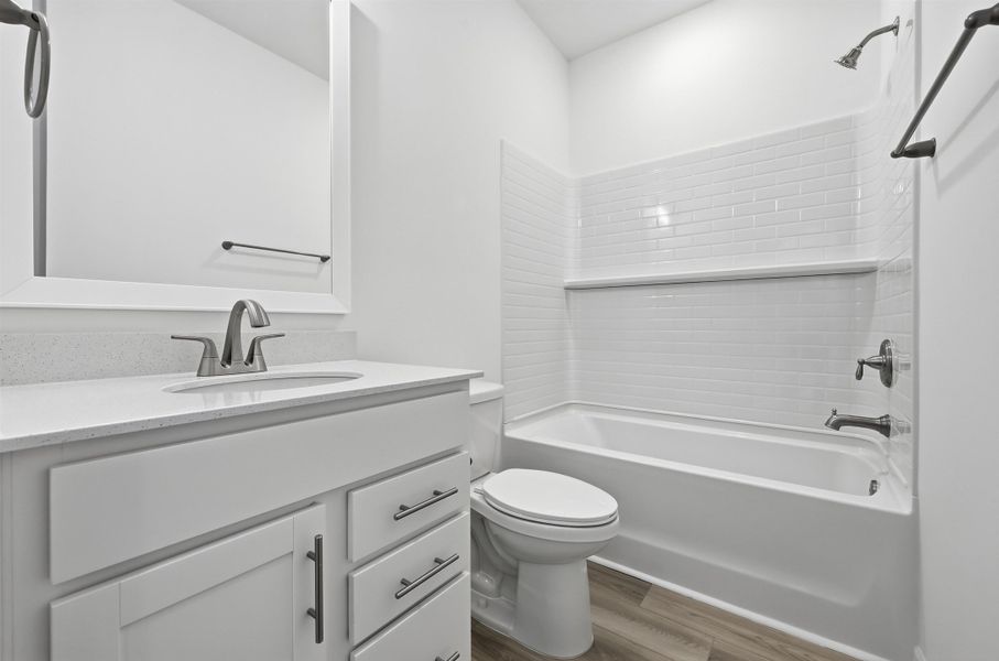 Full bath featuring shower / bathtub combination, vanity, and wood finished floors Full bath featuring shower / bathtub combination, vanity, and wood finished floors