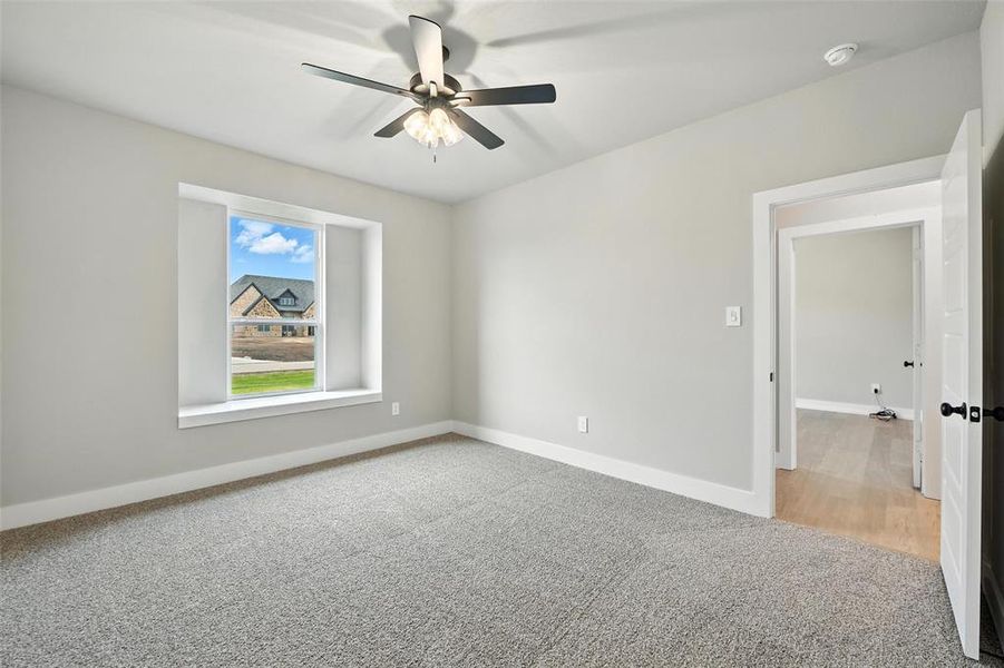 Carpeted empty room with ceiling fan and a smoke detector Carpeted empty room with ceiling fan and a smoke detector