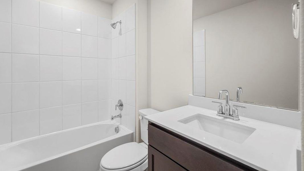 Bathroom featuring a white tiled shower and bathtub, a toilet, a vanity with a white countertop, and a large mirror